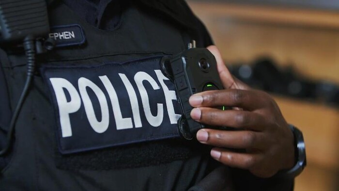 Un policier appuyant ses doigts sur sa caméra-témoin.