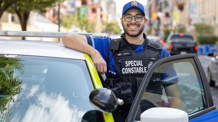 Un agent spécial de la police de London, reconnaissable à son uniforme bleu, à son gilet identifié « agent spécial » et aux marquages distinctifs de son véhicule.