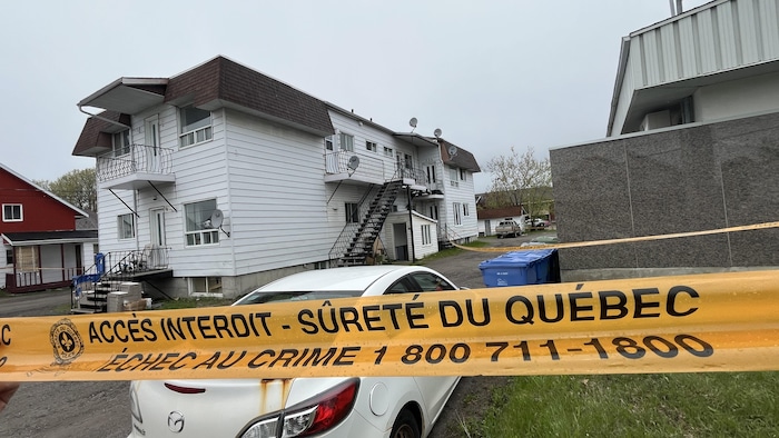 Un ruban jaune de la Sûreté du Québec délimite un périmètre de sécurité autour d'une maison. 