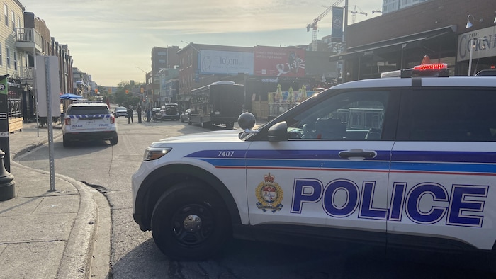 Une voiture de police d'Ottawa est stationnée perpendiculairement à la rue Clarence. Trois policiers debout au centre de la rue parlent à une personne.