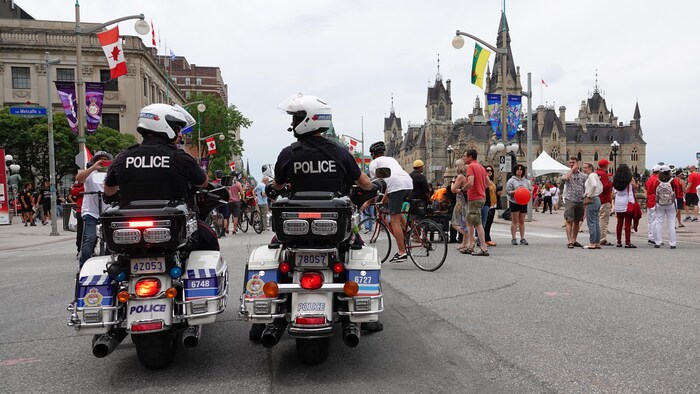 Deux policiers en moto sont à l'arrêt sur la rue Wellington, aux côtés d'une petite foule.