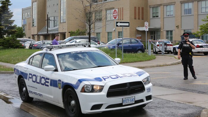 Un policier et une autopatrouille devant une école.