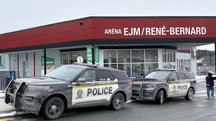 Deux véhicules de police sont stationnés à l'entrée de l'aréna EJM/René-Bernard. 