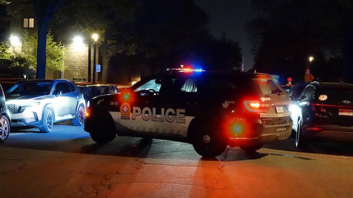Une voiture de police bloquant une rue en soirée