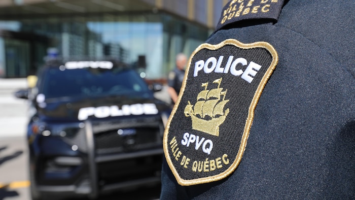 Un policier en uniforme se tenant devant un véhicule d'autopatrouille.