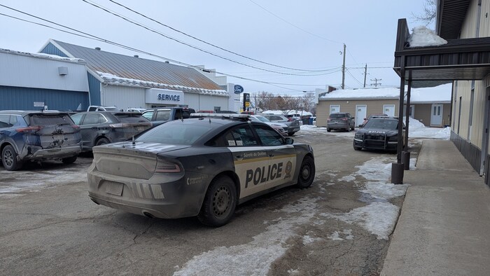 Des voitures de police sont stationnées devant la salle communautaire.