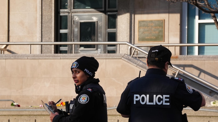 Une agente et un agent prennent des notes sur la scène de crime.