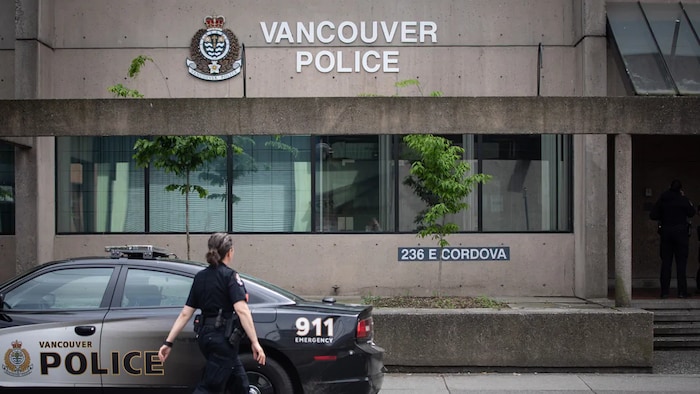 Une policière marche devant une voiture de police et se dirige vers le poste de police de la rue Cordova à Vancouver. 