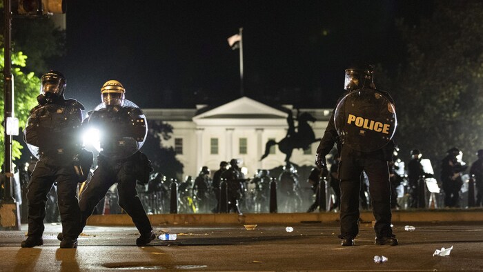 Des policiers en tenue anti-émeute, avec la Maison-Blanche en arrière-plan