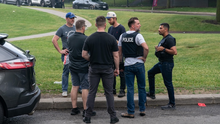 Des personnes et des policiers en groupe sur le gazon à l'extérieur de l'immeuble.