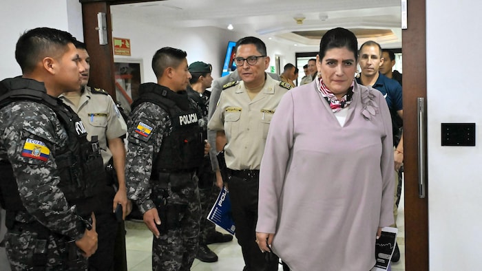 Monica Palencia, escortée par plusieurs policiers, se rend à une rencontre de presse.