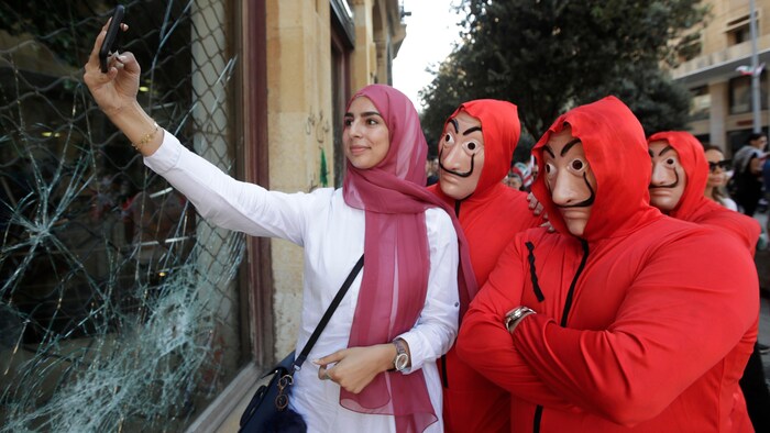 Une femme portant un voile rose prend un égoportrait avec trois personnes arborant le masque de Dali.