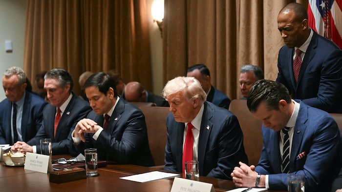 Donald Trump et des hommes de son Cabinet, assis à une table, dans une attitude de prière.