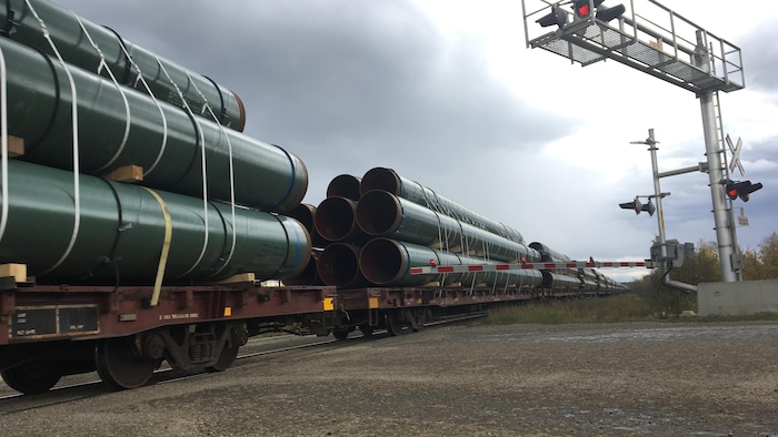 Un bid     chargé de tuyaux destinés aux pipelines traverse un transition  à niveau.