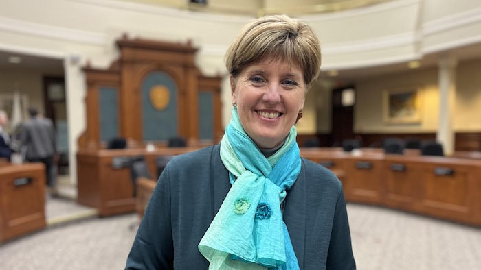 Marie-Claude Bibeau sourit à la caméra. Elle est debout à l'hôtel de ville.