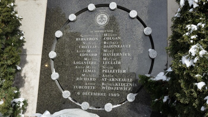 Une gerbe de roses blanches dans la neige, au pied du monument arborant les noms des 14 victimes de la tragédie de Polytechnique.