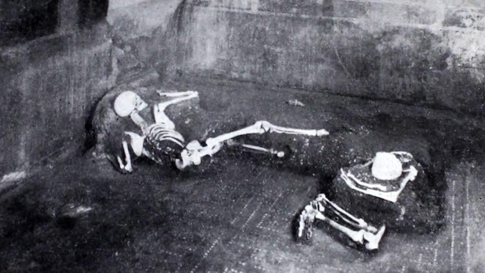 Deux squelettes reposent dans des ruines.