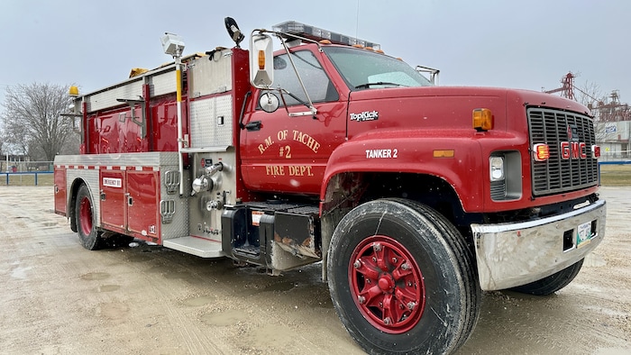 Un camion de pompier rouge sur un chemin de gravier.
