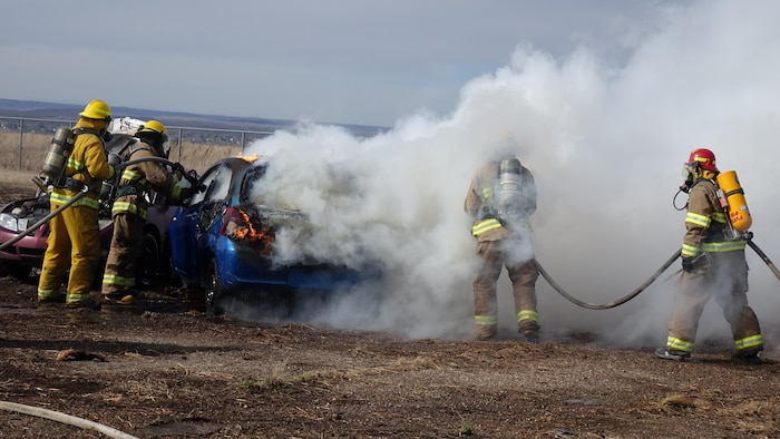 Des pompiers qui combattent un incendie dans un véhicule.