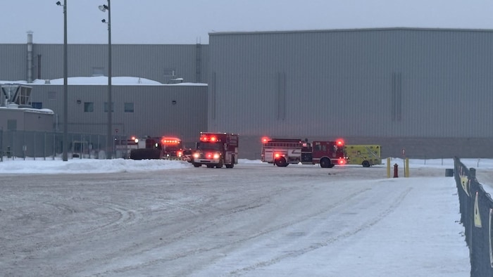 Des camions de pompiers et une ambulance sont à proximité d’un bâtiment en hiver.