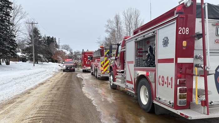 Des camions de pompiers sont immobilisés dans une rue en hiver.