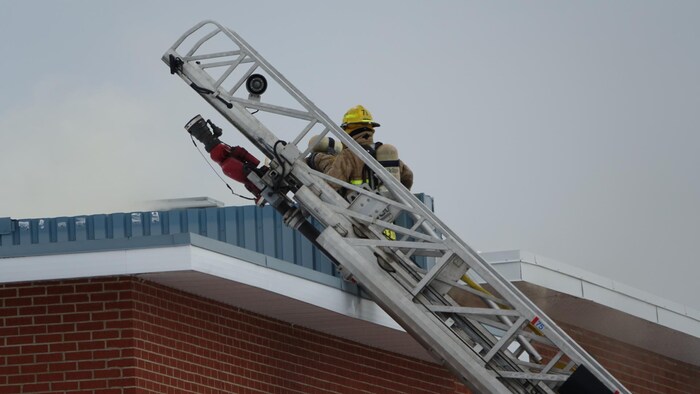 Un pompier dans une échelle sur le toit de l'école Bourg.
