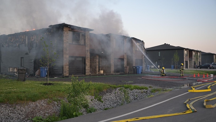 Des pompiers combattent un incendie avec des boyaux. 