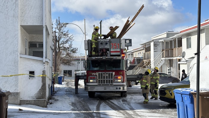 Des pompiers ramassent des morceaux de bois.