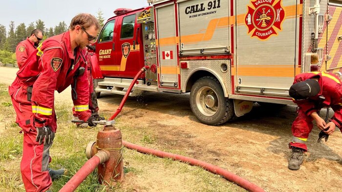 Trois pompiers volontaires s'activent un camion à Weyakwin.
