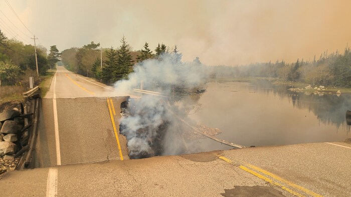 Une route de campagne effondrée avec un nuage de fumée.