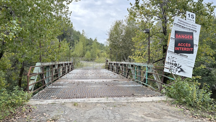 Un pont barré avec une pancarte interdisant l'accès au site.
