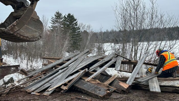 Un travailleur examine des débris de bois.