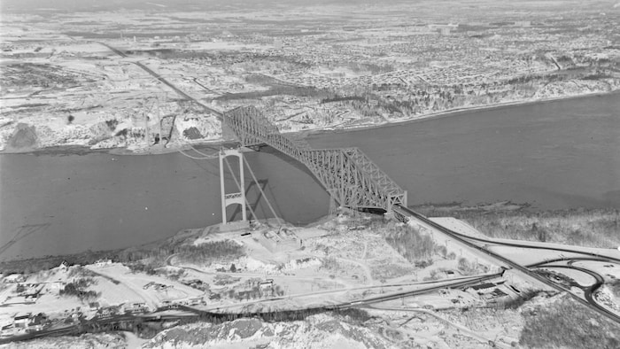 Le pont Pierre-Laporte en construction durant l'hiver, à la fin des années 1960. Le secteur tout autour demeure encore peu densifié. 