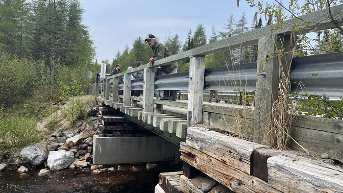 Vue du côté d'un pont où un homme est appuyé et regarde l'eau.