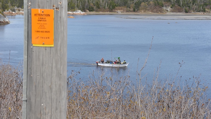 Cinq personnes sont à bord d'un bateau motorisé. Ils traversent la rivière.