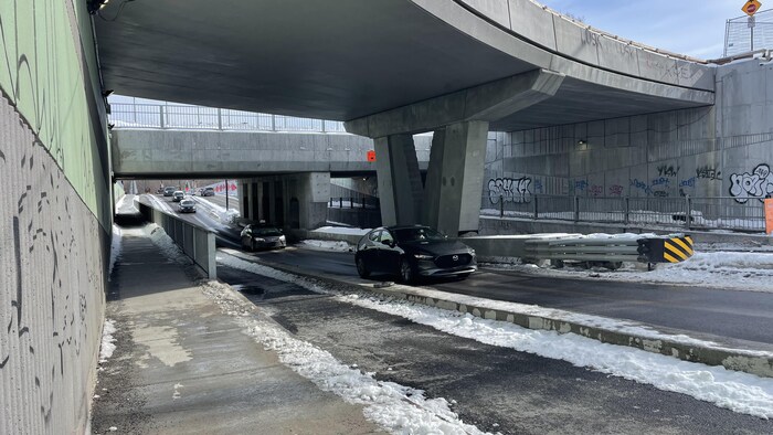 Des voitures qui circulent sous un pont routier.