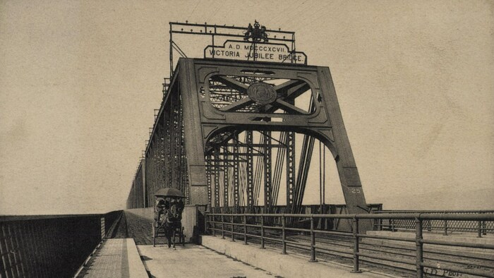 Le pont Victoria vers 1908. Une voiture à cheval circule sur l'étroite voie longeant la structure comprenant les rails.