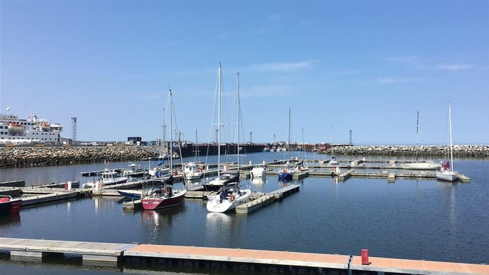 Vue d'ensemble de la marina avec ses pontons, quelques voiliers, l'enrochement et, au fond, le quai réservé à la pêche commerciale