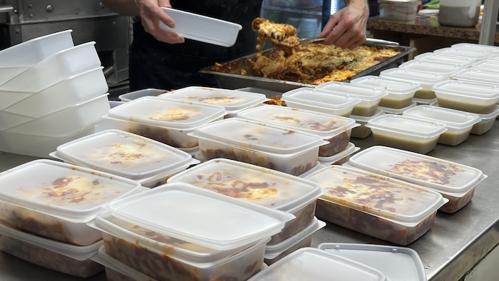 Quelques dizaines de repas dans des contenants sont empilés sur un comptoir, prêts à être livrés.