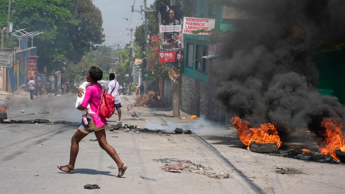 Una mujer con un niño huye tras escuchar disparos en Puerto Príncipe, Haití, el 20 de marzo de 2024. 