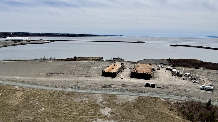 Des employées réparent 2 barges sur un terrain vague au port de Cacouna.  