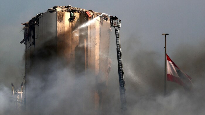 Des pompiers libanais tentent d’éteindre le feu dans le port de Beyrouth.