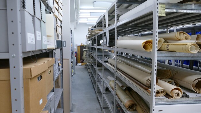 Des rouleaux de papiers disposés sur des étagères.