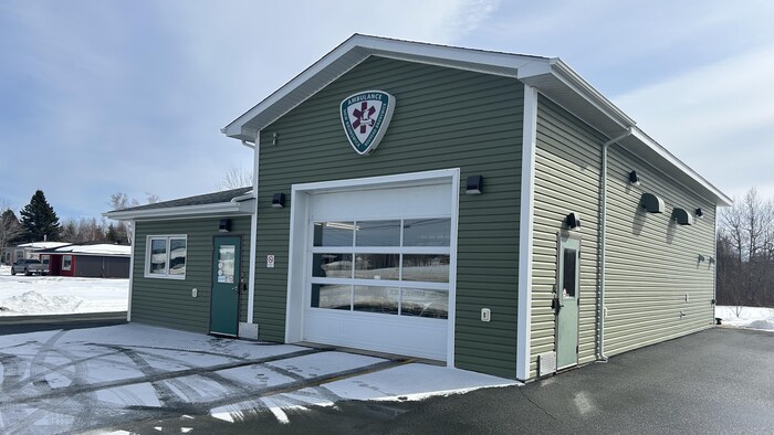 La façade d'un petit édifice, avec une grande porte de garage.