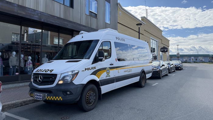 Une camionnette de la Sûreté du Québec est stationnée dans une rue en face d'un commerce.
