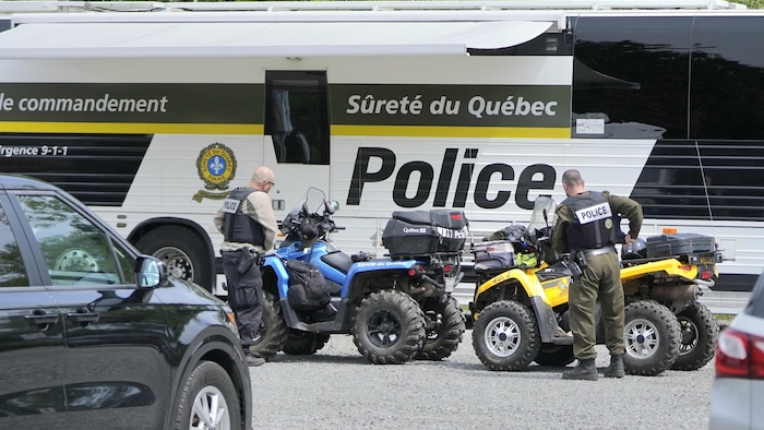 Des policiers près d'un poste de commandement avec des véhicules tout-terrain.