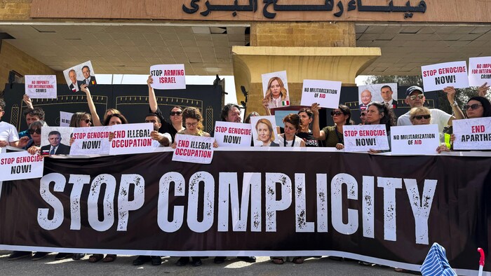 Des hommes et des femmes debout portant une banderole et des pancartes.