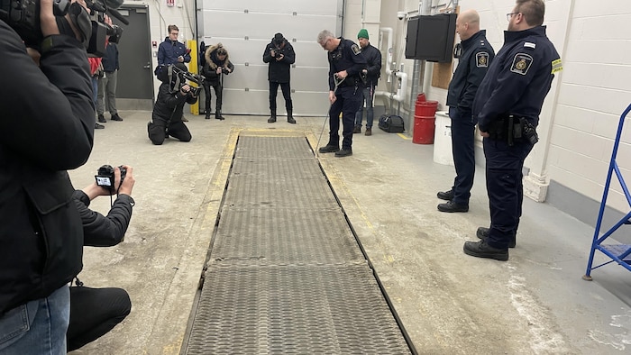 Une personne ouvre une grille sous les regards de collègues.