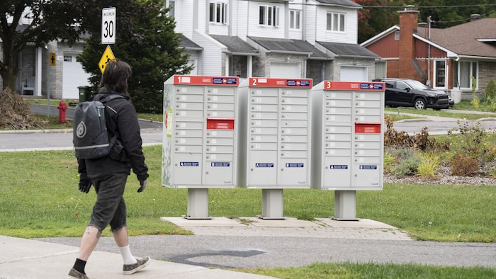 Un homme marche près de boîtes postales communautaires.