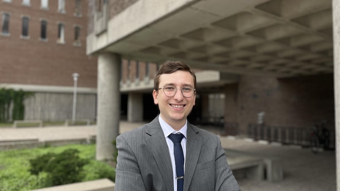 Portrait de Vincent Larochelle, dehors, devant un pavillon de l'Université de Montréal.